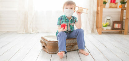 Little cute kid boy in quarantine at home dreams of traveling.