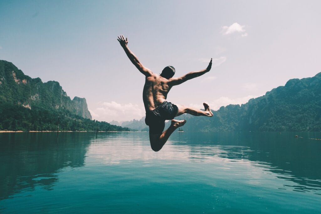 Man jumping into lake with mountains